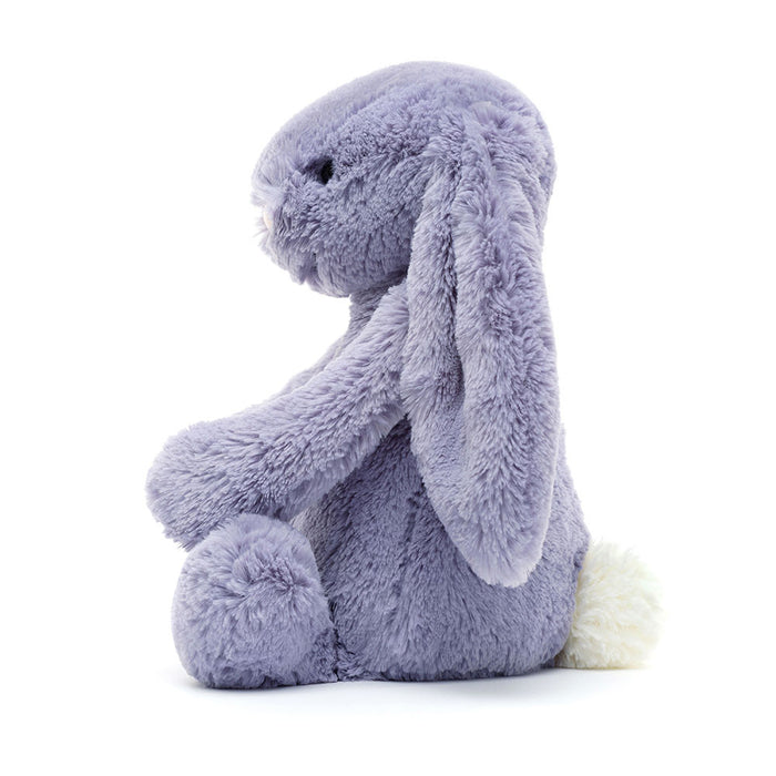 Side view of a plush toy rabbit in purple on a white background