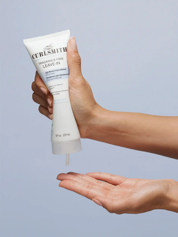 Curlsmith leave-in product being applied to a hand against a light gray background