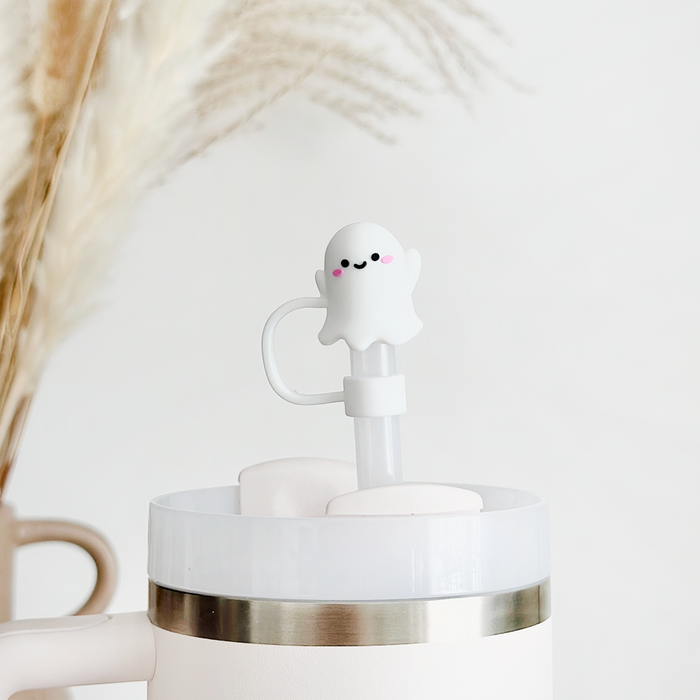 White cup with lid topped by Coconut Lane silicone ghost straw cover, set against a backdrop of dried grass.