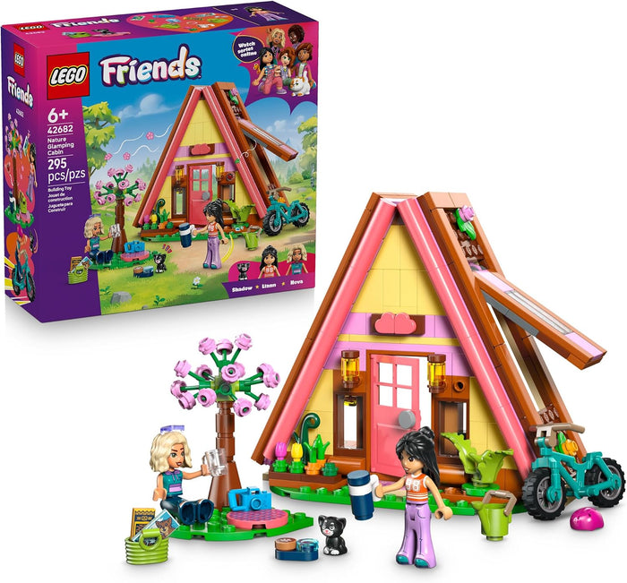 LEGO Friends Stephanie's A-Frame Cabin building set, showing the assembled colorful cabin with mini-dolls, bicycle, tree, and accessories in front, alongside the retail box on a white background.