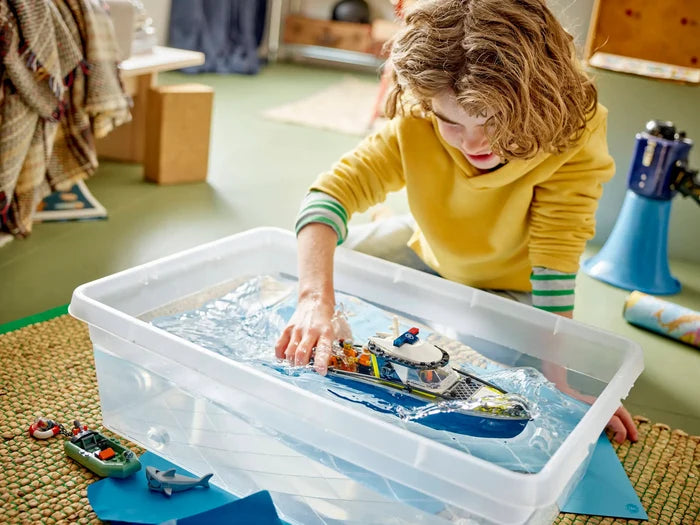 Child playing with toy boats in a water table indoors