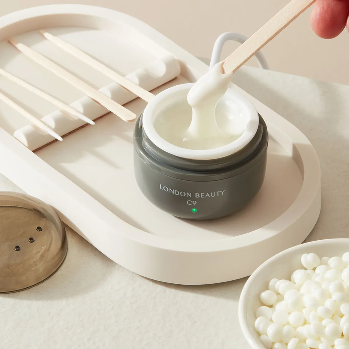 stirring a mini wax heater with waxing pellets from the london beauty company