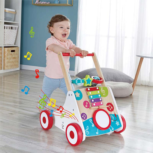 Child playing with a colorful toy walker in a room with musical notes graphics.