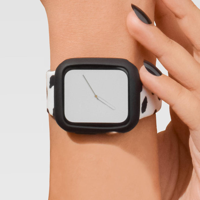 Apple Watch with a cow-print band and blank face in a black Coconut Lane silicone case on a wrist.