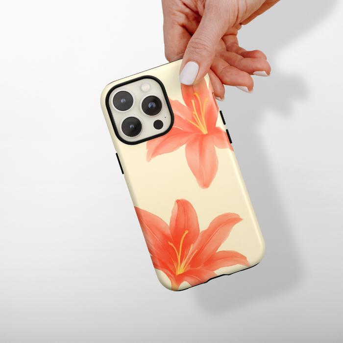 Hand holding a Coconut Lane Tough MagSafe phone case with orange lilies on a cream background.
